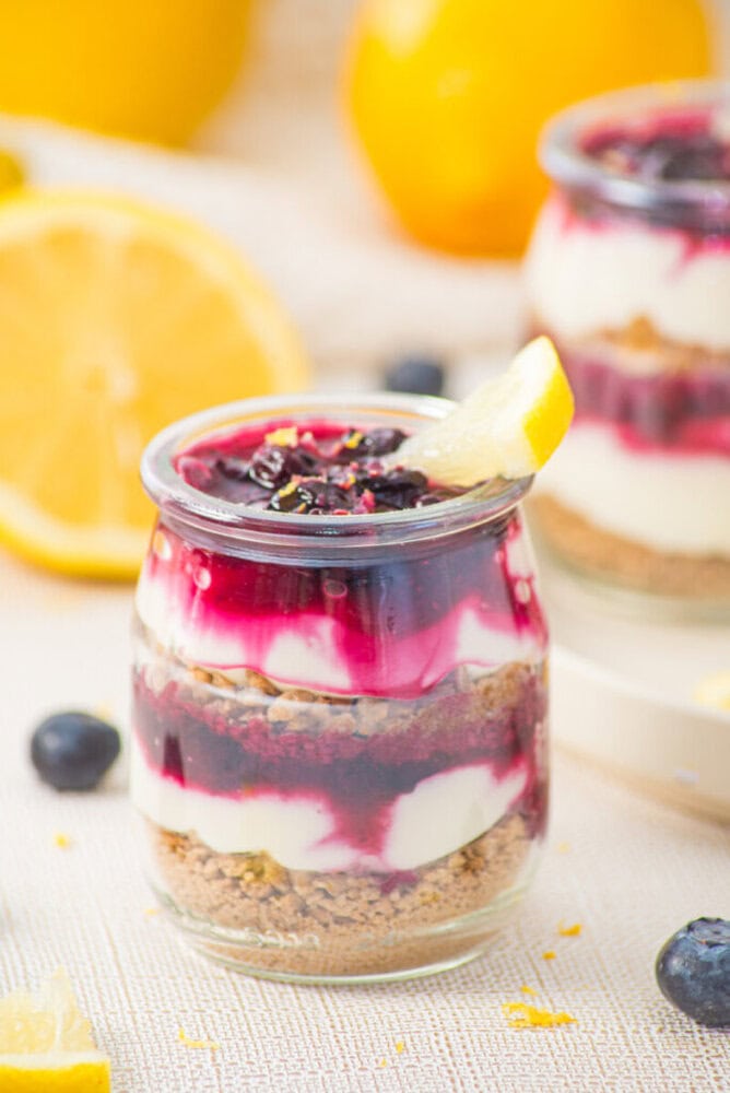 Delicious lemon blueberry cheesecake parfait in a glass jar with layers of creamy cheese, blueberry.