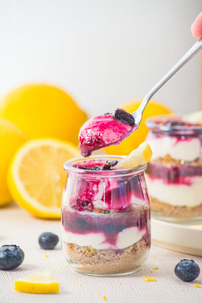 Delicious berry cheesecake parfait in a glass with layers of cream, berries, and crust.