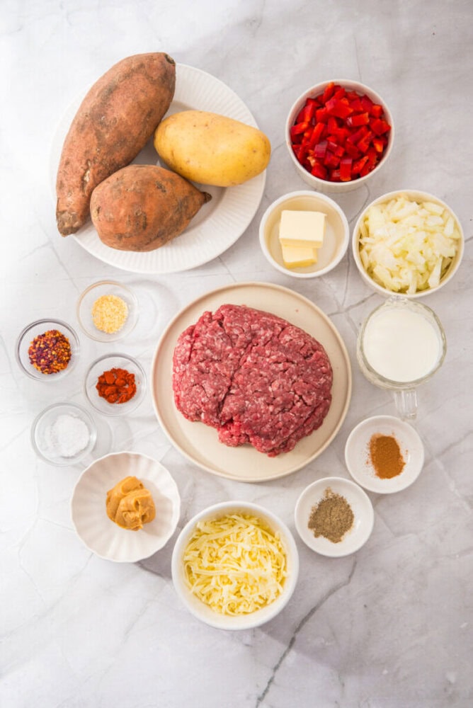 Fresh sweet potatoes, ground beef, and vegetables for hash recipe.