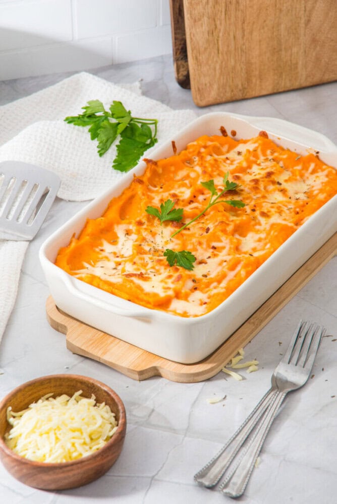Delicious baked pasta with melted cheese and herbs in a white casserole dish.