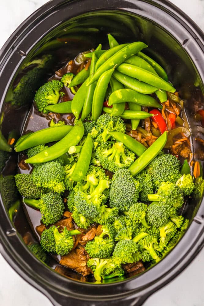 Slow cooker vegetable stir fry with broccoli, snap peas, and red bell peppers. Perfect for a nutriti.
