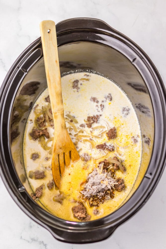 Slow cooker beef stew with tender meat and rich, savory broth in a black crockpot.