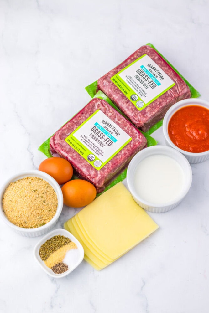 Ground beef with spices and eggs on a white surface.