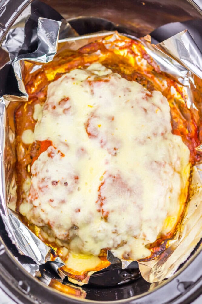 Delicious homemade baked lasagna with melted cheese and rich tomato sauce in foil packaging.