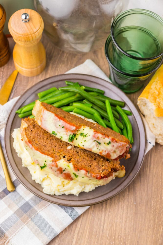 Breaded fish fillet served with fresh green beans and creamy mashed potatoes on a rustic plate.