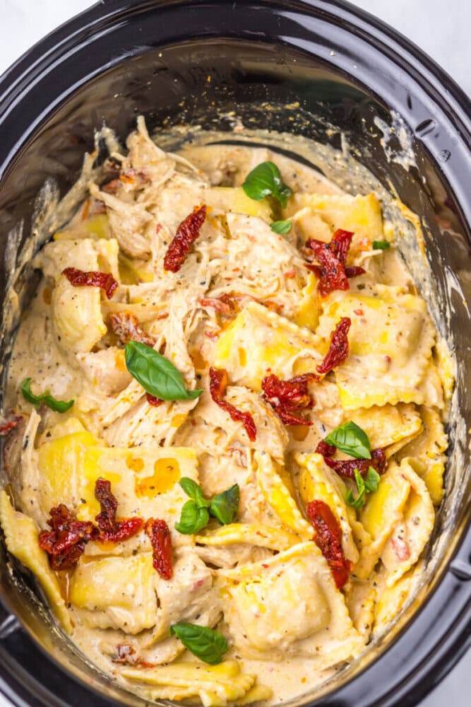 Creamy chicken Alfredo pasta with sun-dried tomatoes and basil in a glass dish.