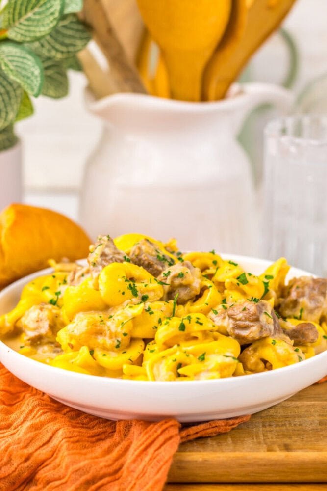 Delicious creamy chicken and potato pasta served in a white bowl with herbs.