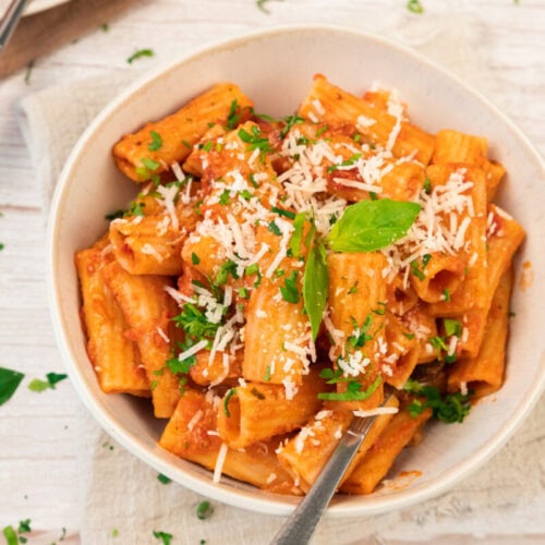 Delicious creamy tomato pasta garnished with fresh basil and grated cheese.