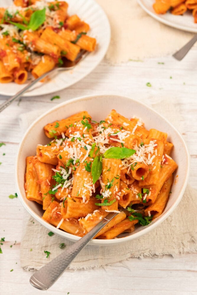 Delicious creamy tomato pasta garnished with fresh basil and grated cheese.