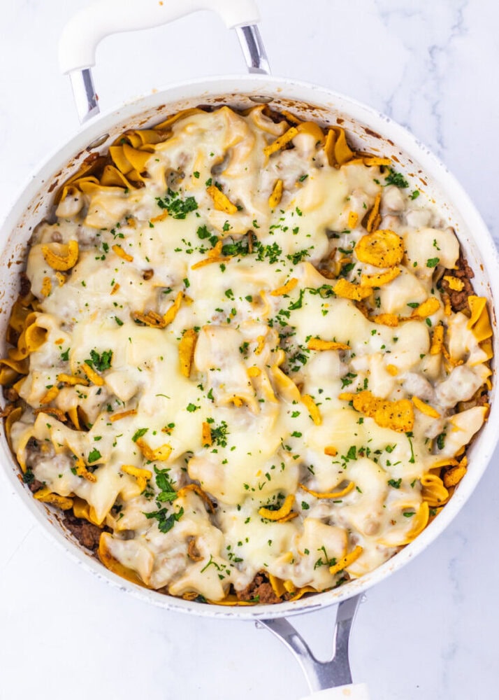 Delicious creamy chicken and mushroom pasta baked with melted cheese, garnished with fresh herbs. Pe.