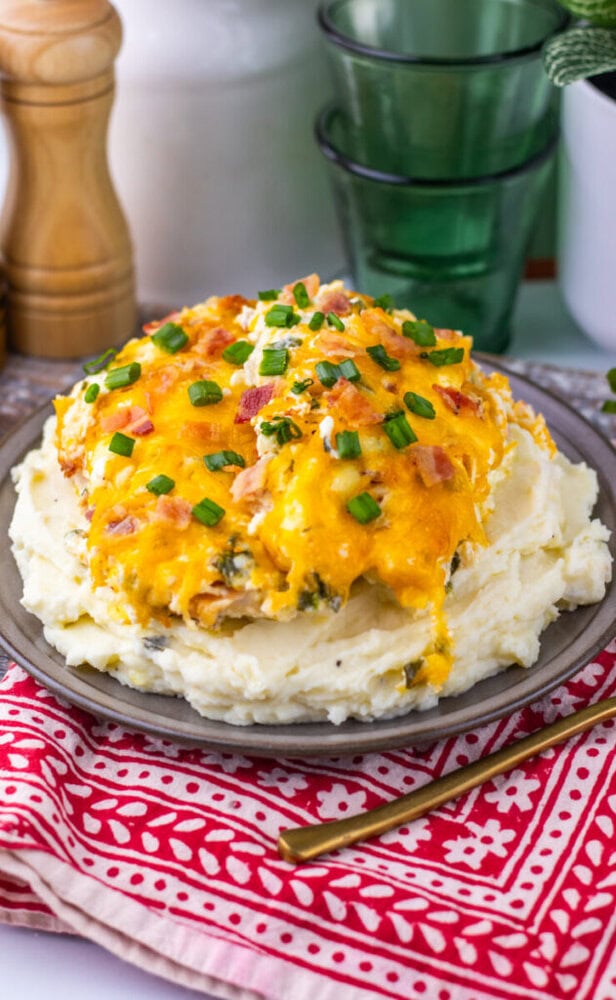 Hearty chicken and mashed potatoes topped with cheese and green onions on a plate.