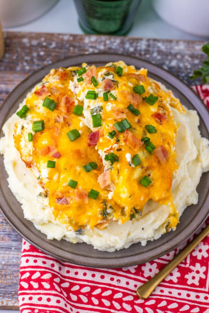Creamy mashed potatoes topped with cheese, ham, and green onions, served hot.