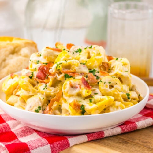 Delicious creamy chicken pasta salad with vegetables and herbs in a white bowl.