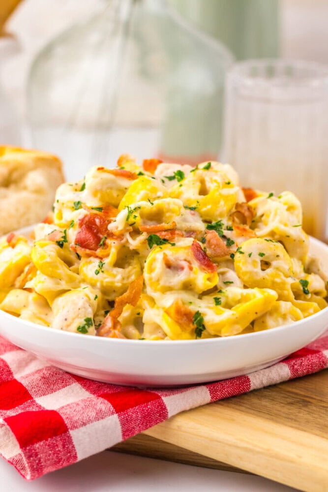 Delicious creamy chicken pasta salad with bacon and herbs in a white bowl.