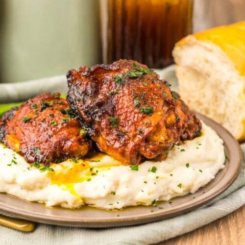 Juicy beef ribs served with creamy mashed potatoes and fresh bread on a rustic plate.