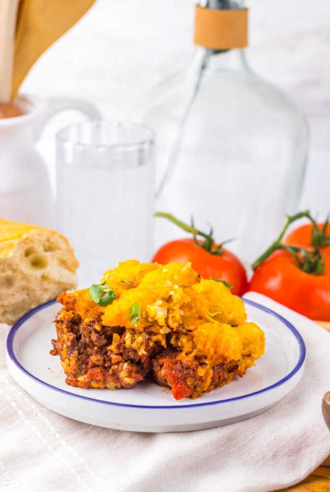 Delicious cheeseburger meatloaf topped with melted cheese and fresh herbs, served on a white plate.