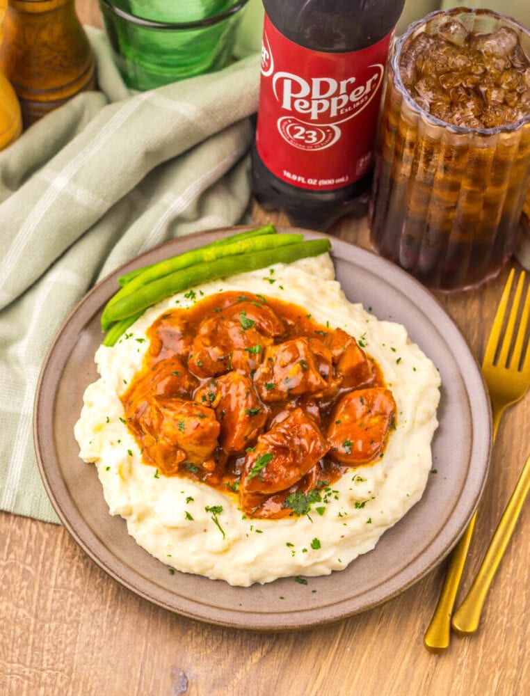 Chicken pot pie served over mashed potatoes with soda and ice, on a wooden table.