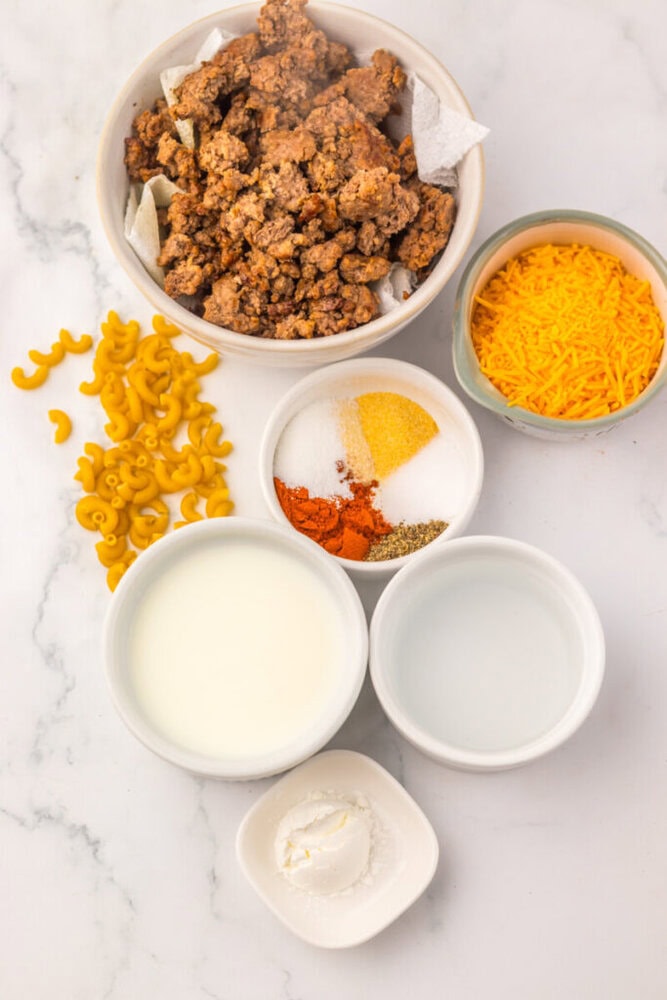 Crispy fried chicken served with shredded cheddar, spices, and milk on a white marble surface.