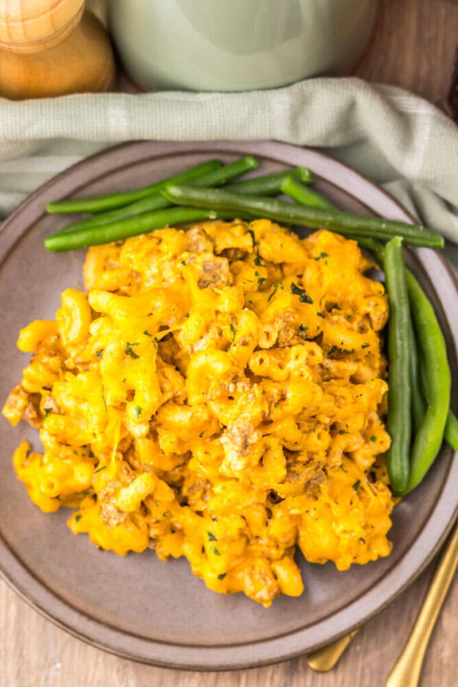 Delicious creamy mac and cheese served with fresh green beans on a rustic plate.