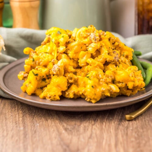 Delicious creamy scrambled eggs garnished with herbs on a brown plate.