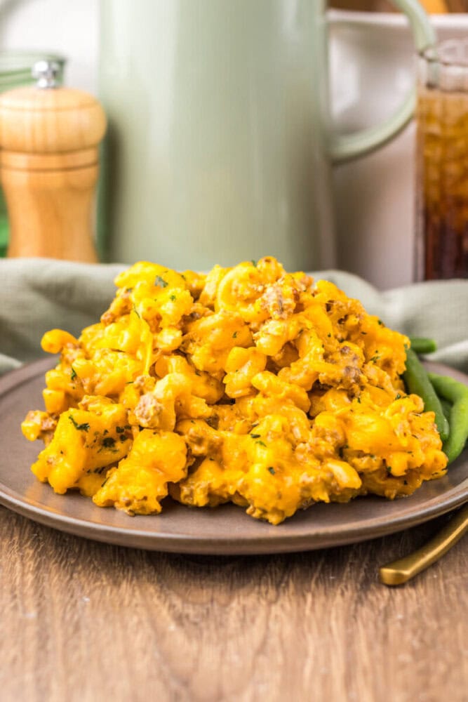 Creamy cheesy mashed potatoes served with fresh green beans on a rustic plate.