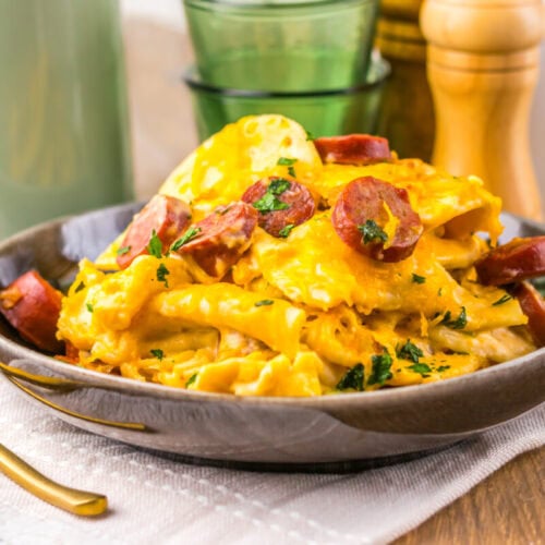 Delicious creamy sausage and egg pasta served in a dark bowl with herbs.