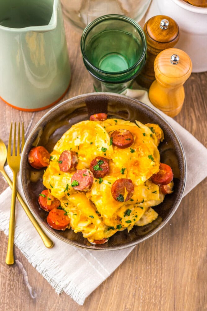 Delicious sausage and eggs breakfast skillet with herbs, served in a rustic bowl. Perfect for a hear.