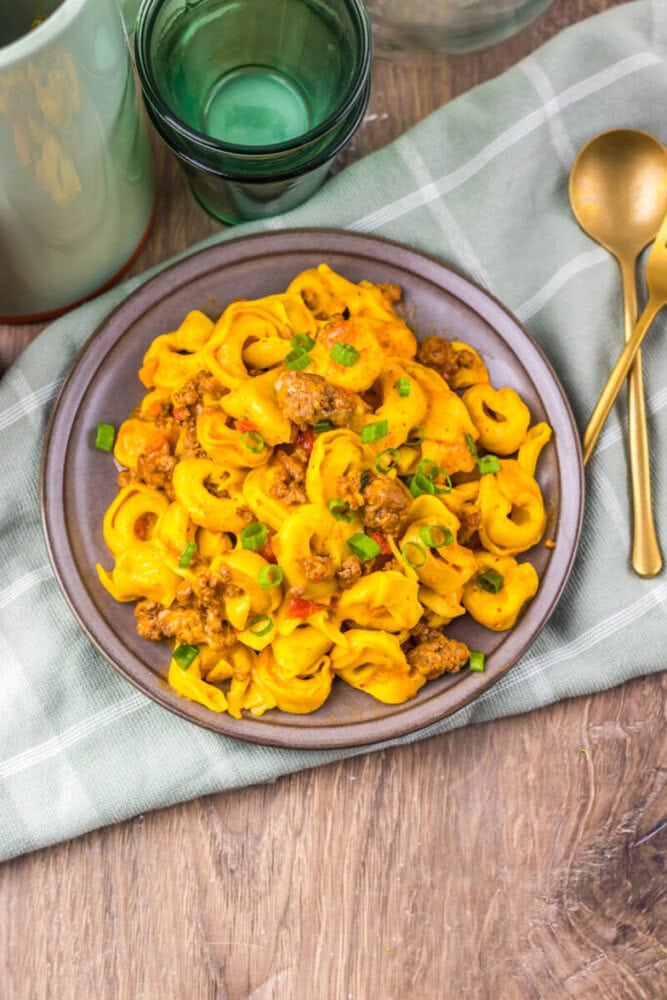 Delicious creamy beef and pasta skillet garnished with green onions on a rustic wooden table.