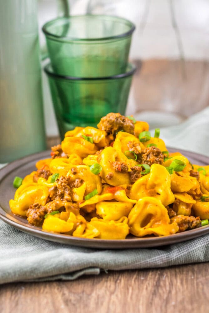 Delicious pumpkin tortellini with ground beef and creamy sauce on a rustic wooden table.