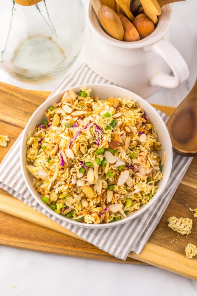 Delicious creamy chicken salad with nuts, vegetables, and herbs in a white bowl.