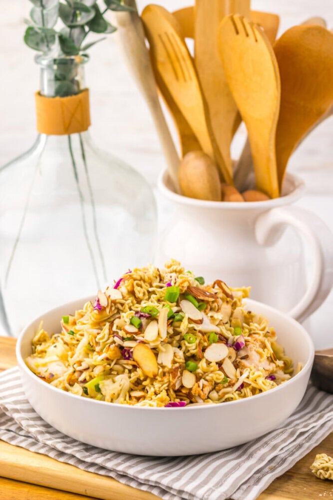 Delicious chicken salad with nuts, vegetables, and herbs in a white bowl.
