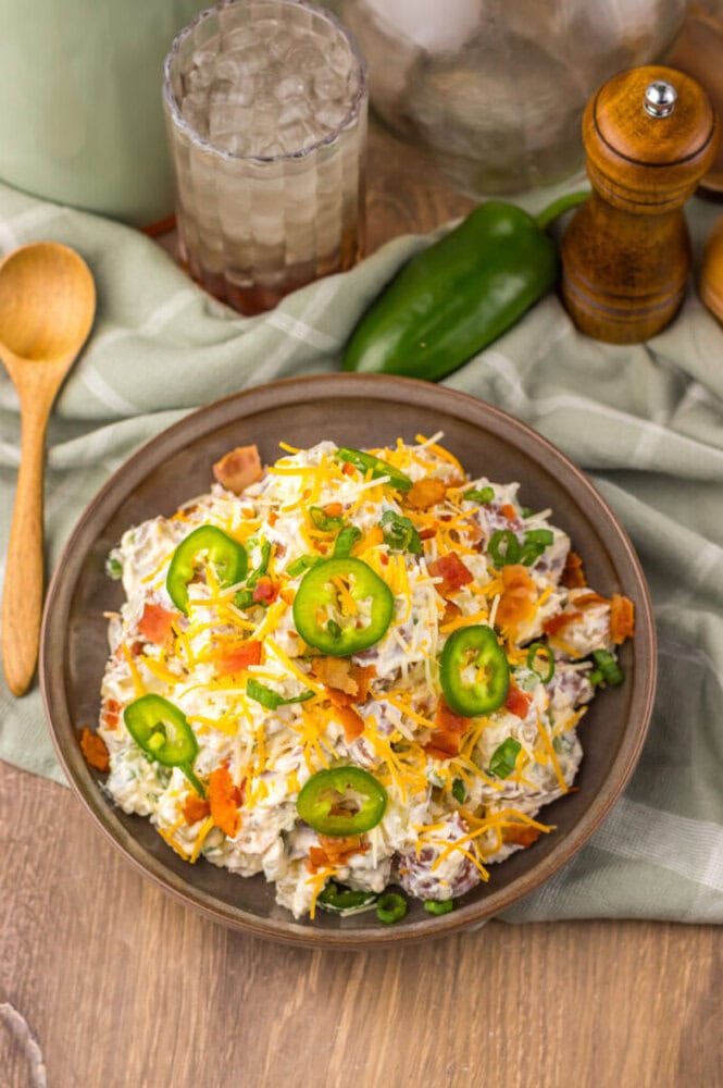 Creamy chicken salad with cheese, jalapeños, and fresh vegetables in a bowl.
