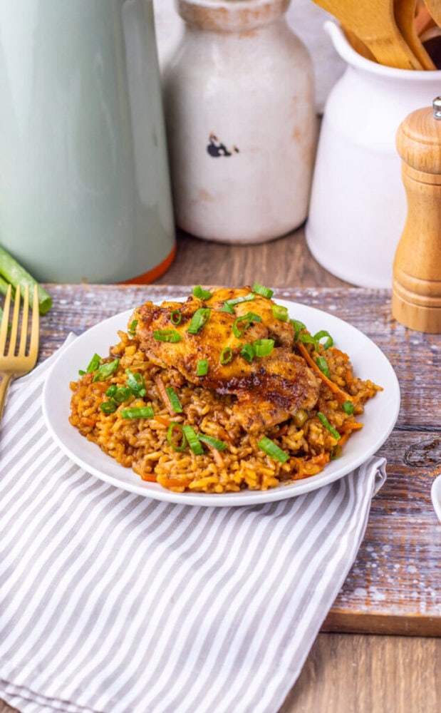Japanese BBQ chicken served over teriyaki fried rice garnished with green onions on white plate
