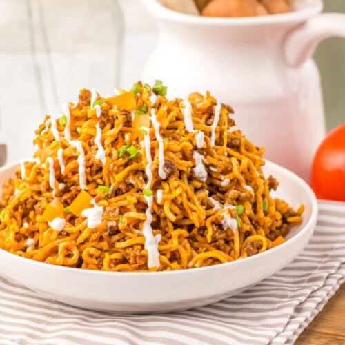 Delicious spicy chicken fried rice garnished with green onions and drizzled with white sauce. Perfec.