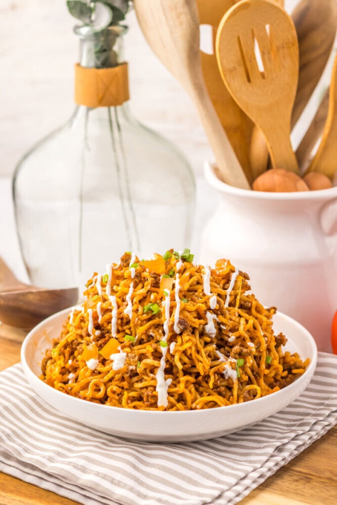 Delicious spicy chicken ramen noodles garnished with sauce and herbs.