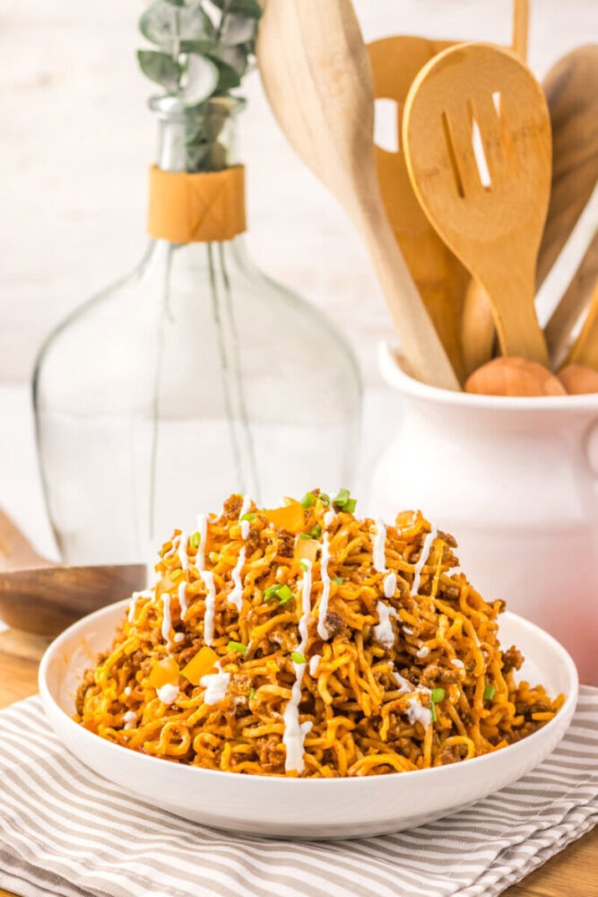 Delicious spicy chicken ramen noodles garnished with green onions and drizzled with sauce.