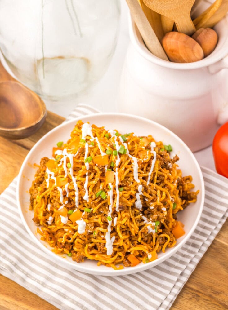 Delicious spicy chicken ramen noodles garnished with green onions and drizzled with sauce.