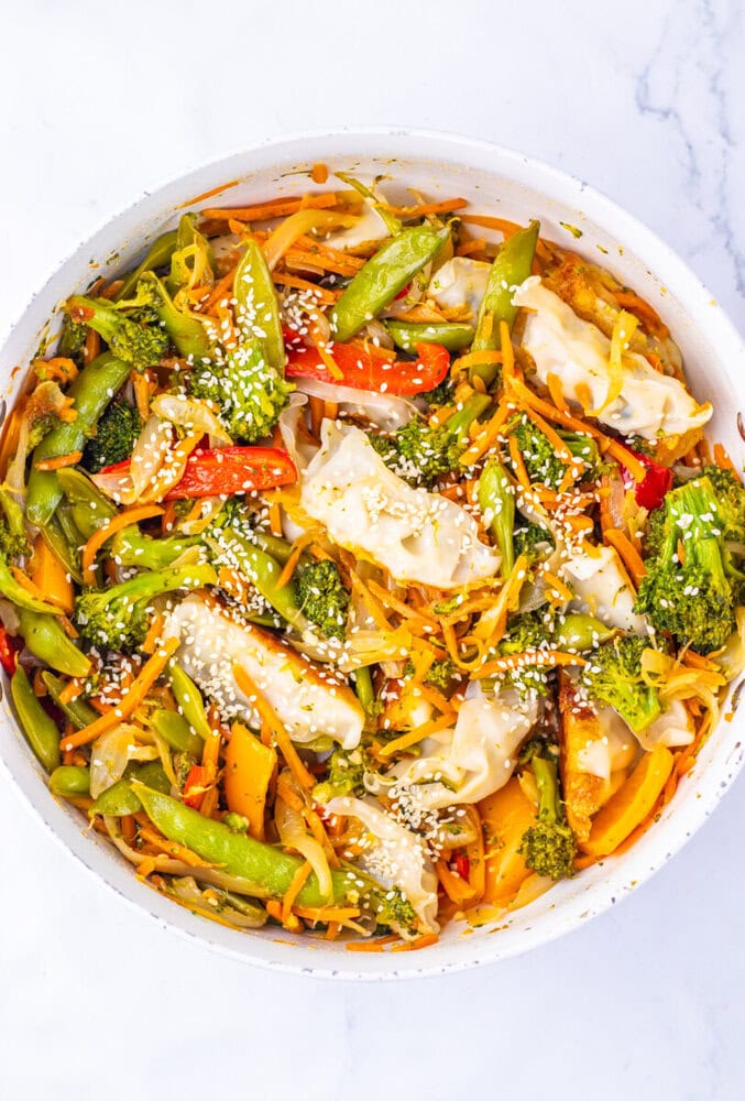 Colorful stir-fried vegetables with broccoli, peppers, and carrots in a white bowl.