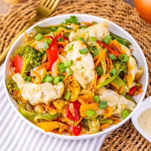 Vibrant vegetable stir-fry with dumplings, bell peppers, broccoli, and sesame seeds.
