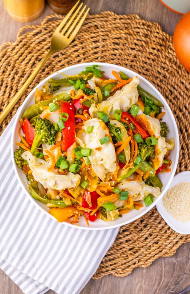 Vibrant vegetable stir-fry featuring dumplings, broccoli, bell peppers, and carrots in a savory sauc.