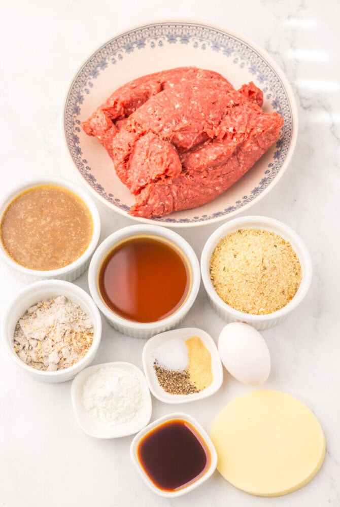 Raw ground beef on a plate with seasoning ingredients.