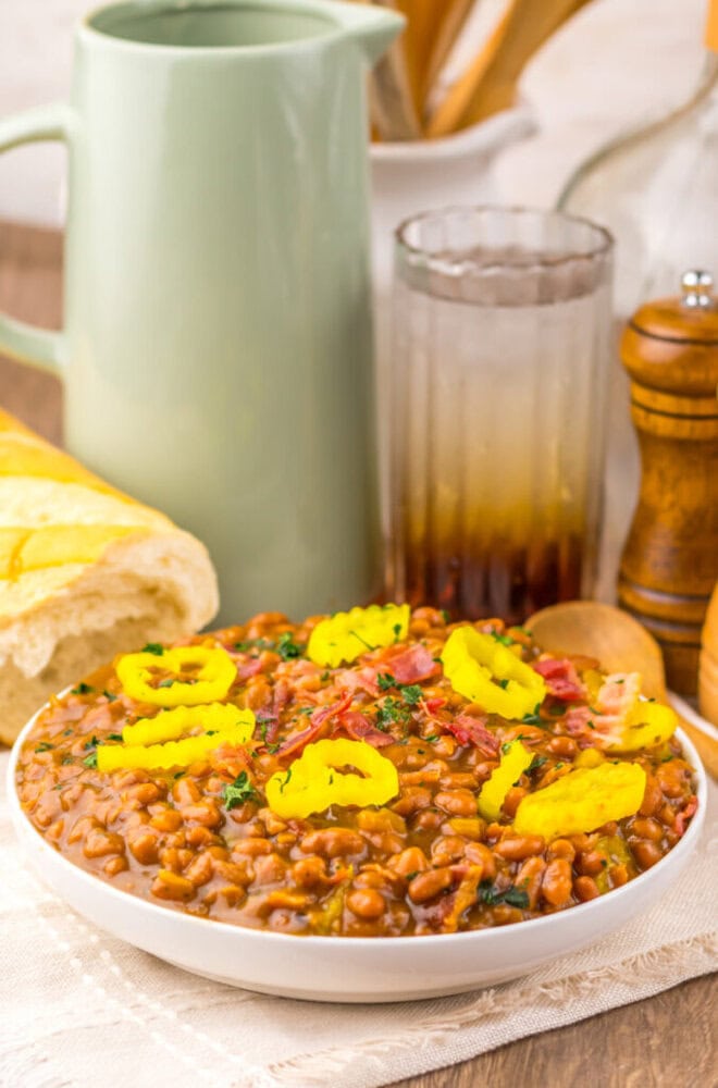 Delicious bean chili topped with yellow peppers and herbs, served in a white bowl.