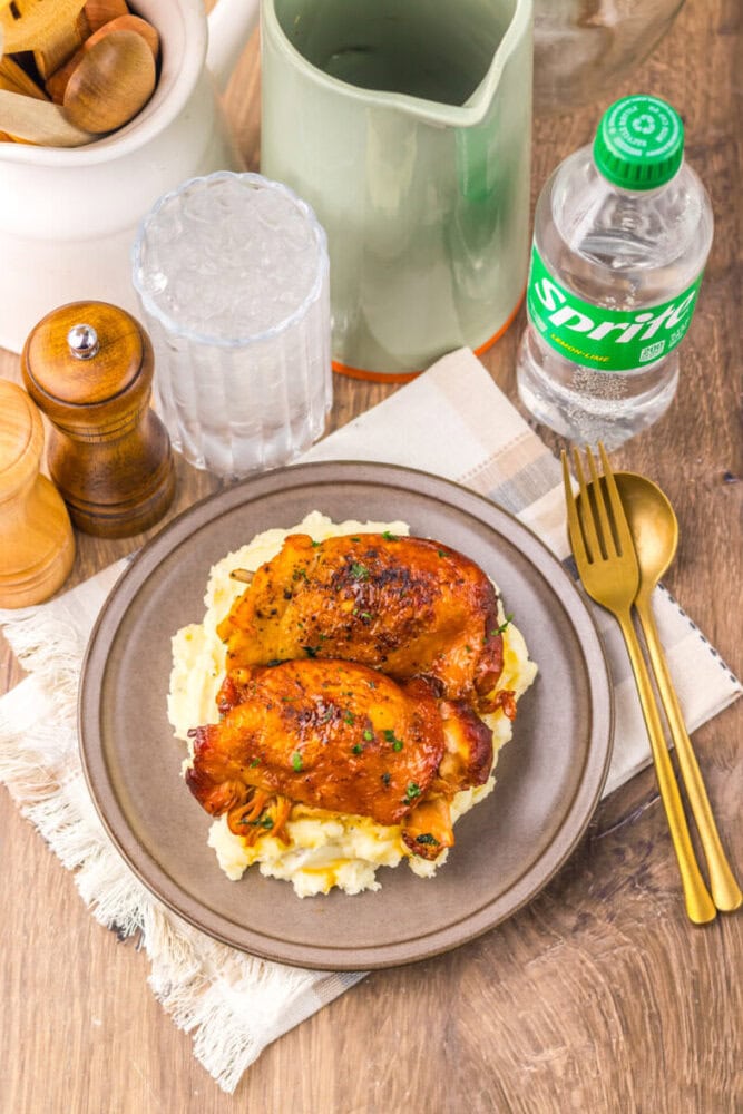 Baked chicken thighs with crispy skin served over creamy mashed potatoes, perfect for a hearty and f.