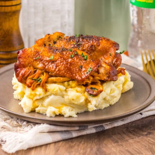 Juicy roast chicken served over creamy mashed potatoes on a rustic plate.