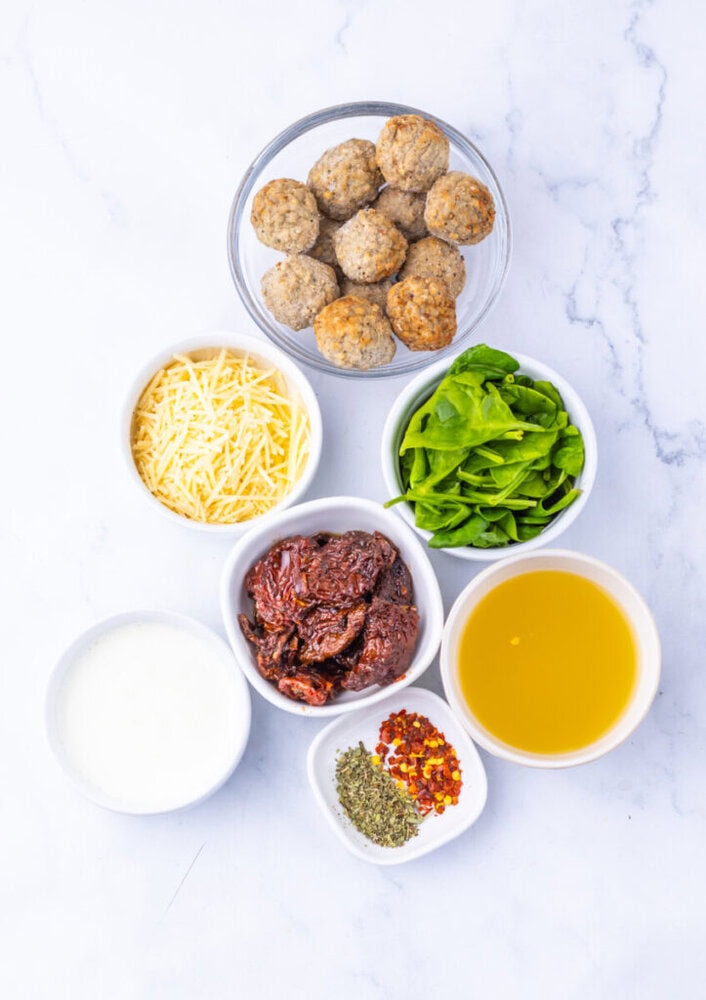 Delicious homemade meatballs with cheese, spinach, and spices on a white marble background.