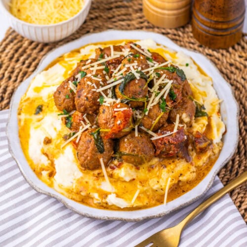 Delicious creamy beef and vegetable pasta topped with cheese on a white plate.