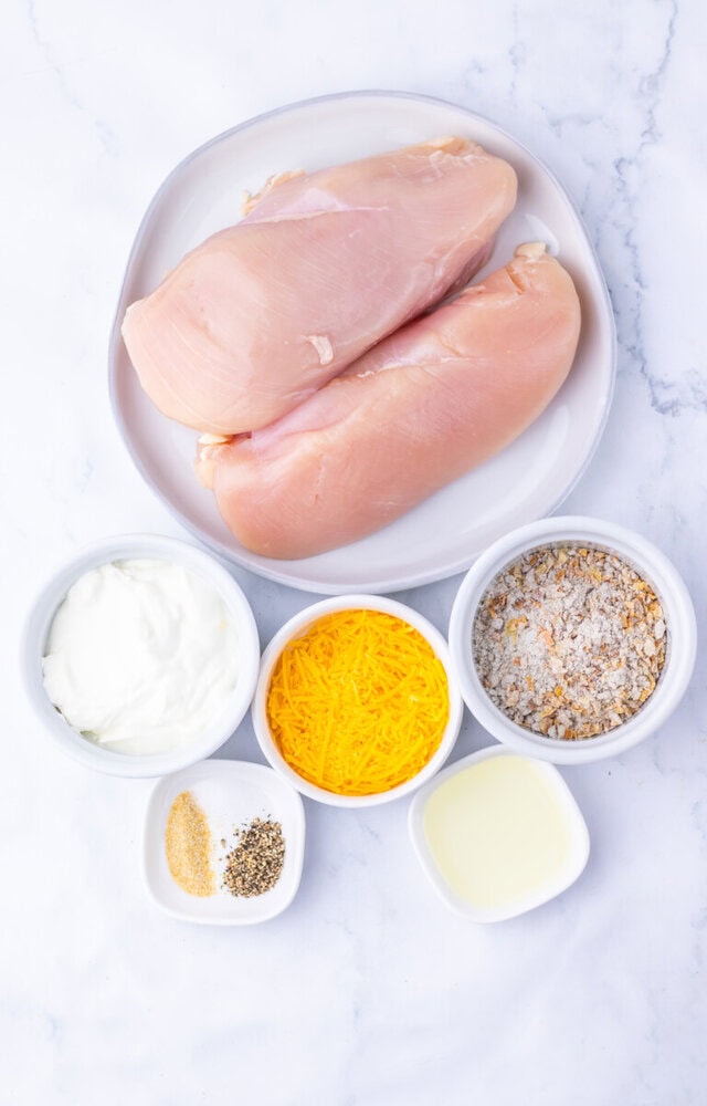 Sour cream and onion chicken recipe ingredients - raw chicken breasts and measured toppings on marble