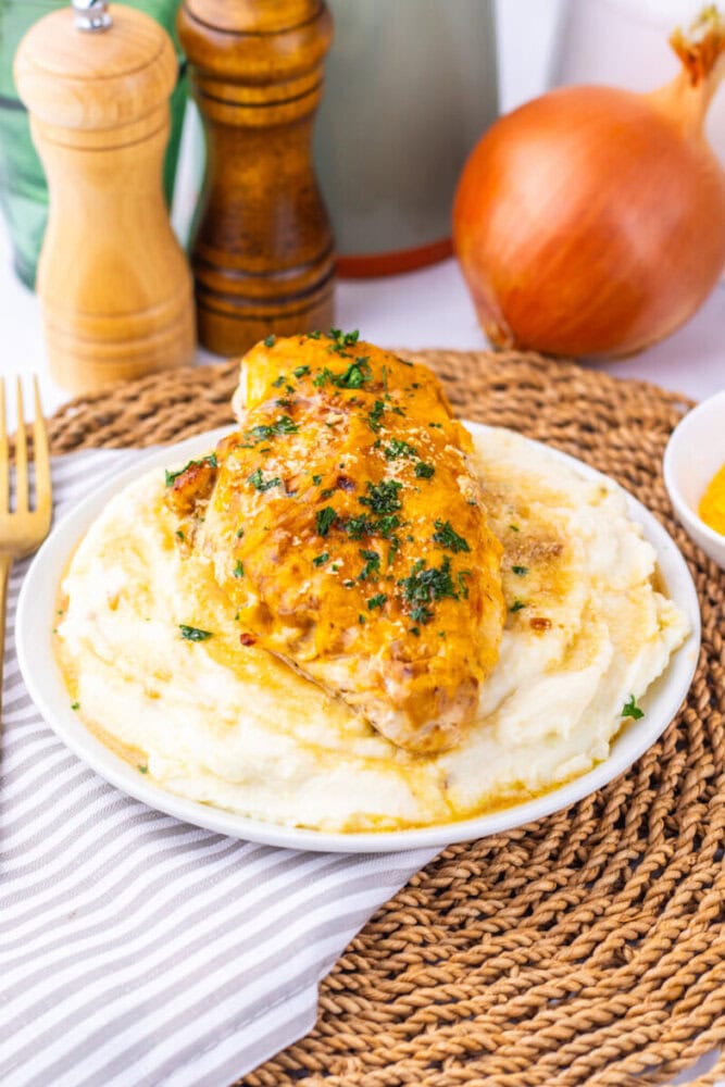 Delicious baked chicken breast topped with herbs served over creamy mashed potatoes.
