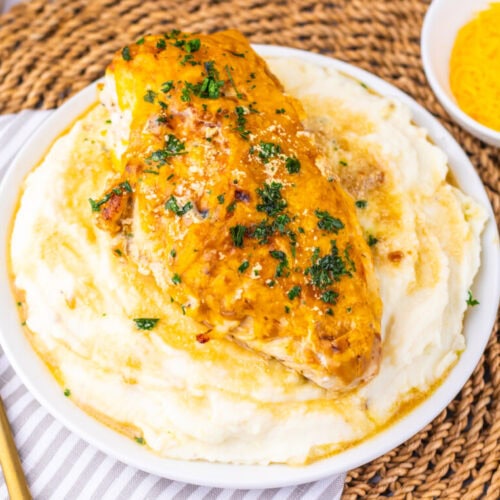 Delicious baked chicken breast served over creamy mashed potatoes with herbs.