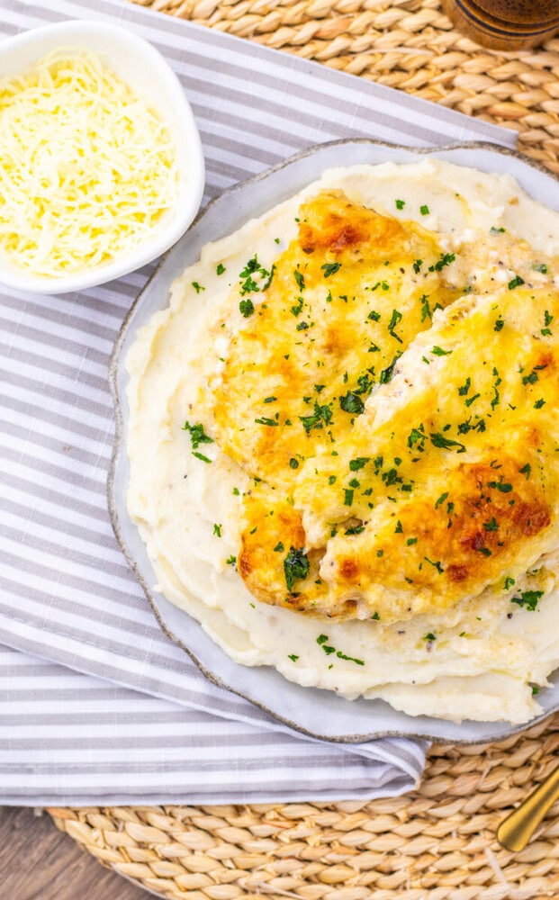 Creamy chicken Caesar bake with golden cheese topping and parsley garnish served with mashed potatoes